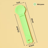 Mint green baby rattle with measurements on a beige background