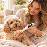 A woman in a cozy living room sits on a couch with a small fluffy tan dog, holding a white digital thermometer to the dog's paw.